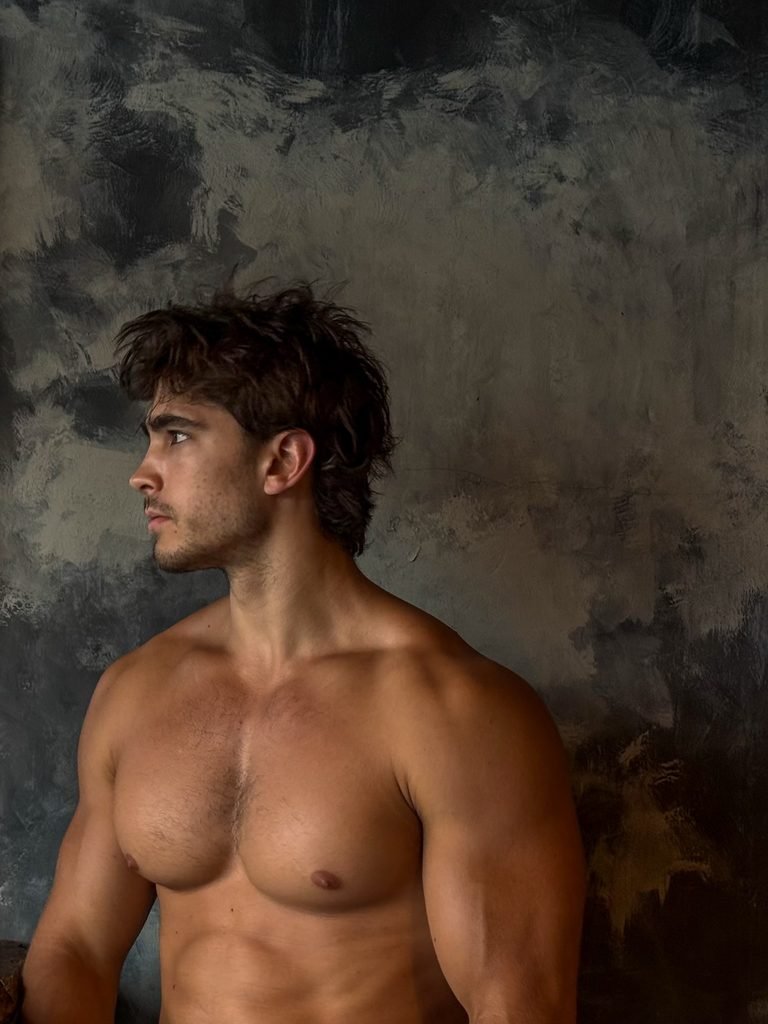 Kyle Kuznik flexing in the gym, muscle on display